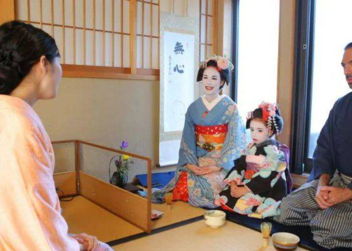 A family at a Japanese tea ceremony; the mother and daughter are dressed in traditional geisha attire.